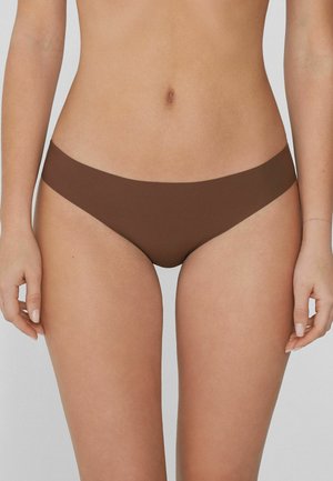 Donna che indossa mutande marroni a vita bassa senza cuciture, in piedi con le braccia rilassate ai lati contro uno sfondo neutro.