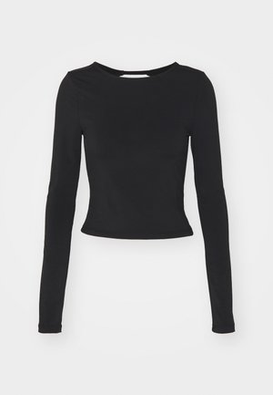 Černý dlouhý rukáv crop top s kulatým výstřihem, přiléhavým střihem a hladkou texturou. Spodní lem sedí těsně nad pasem.