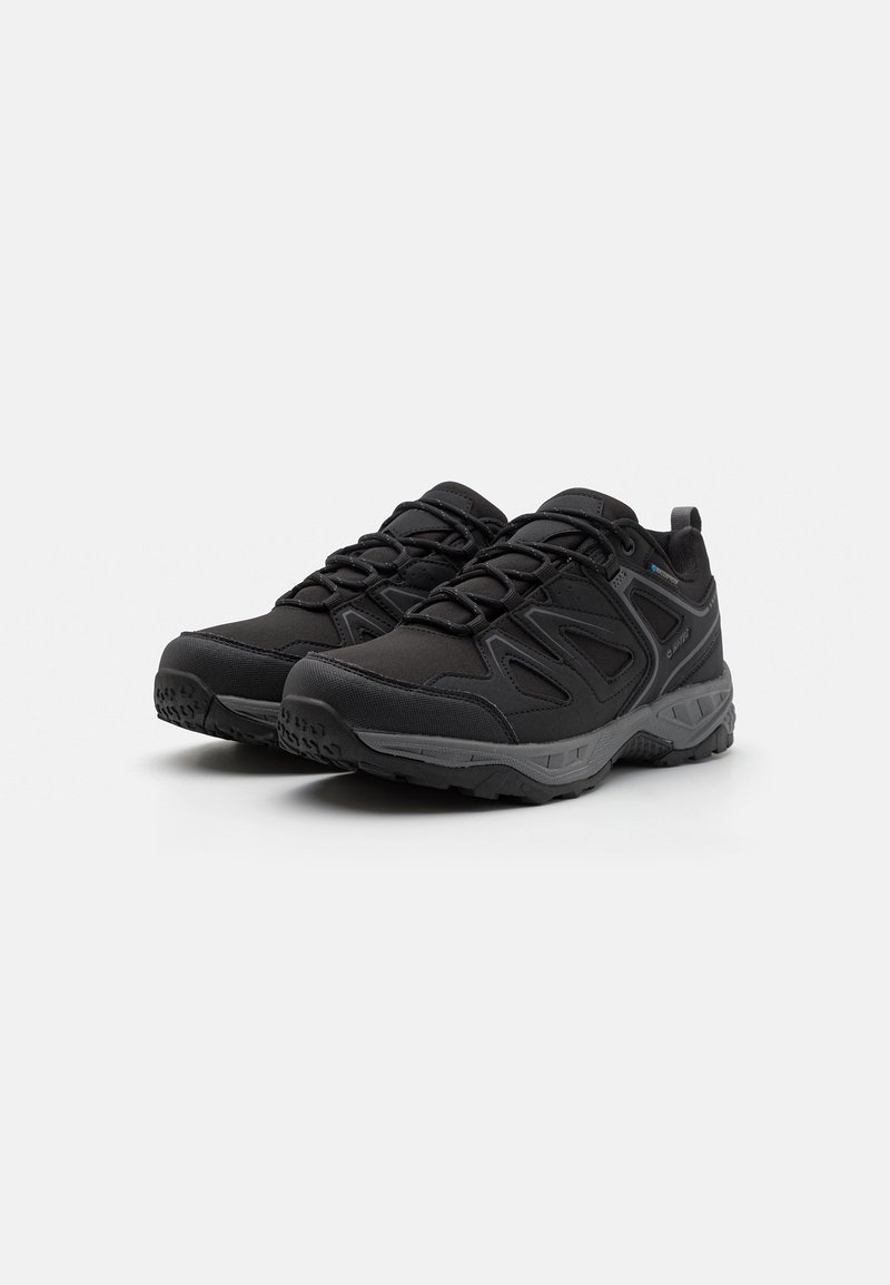 Schwarze Sportschuhe mit einem strukturierten Obermaterial, verstärkter Zehenpartie und flexibler Sohle. Mit elastischen Schnürsenkeln und einer kleinen Zuglasche an der Ferse.