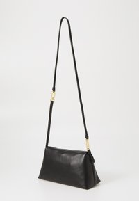 Sac à main en cuir noir avec une forme structurée, une bandoulière amovible et des ferrures en ton doré. Texture lisse avec un design minimaliste.