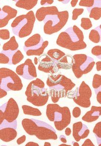 Leopardmönstrad textil med bruna och lavendellila fläckar på en krämfärgad bakgrund. Broderad logotyp "hummel" i silver. Mjukt, stickat tyg.
