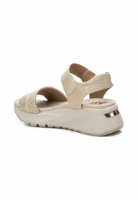 Sandalias de cuña beige con diseño perforado, tiras de ante, banda elástica y suela texturizada blanca con un acento dorado en el talón.