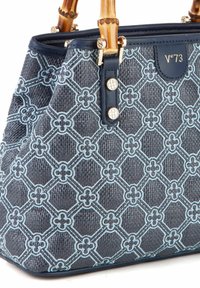 Un sac à main texturé bleu marine présente un motif floral léger complexe en bleu ciel, des poignées en bambou et des accents en métal doré.