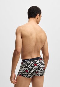 Boxers negros con un logo repetido de "HUGO" en blanco y rojo. Tela suave y elástica con una cómoda cinturilla elástica.