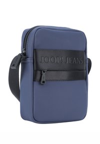 Borsa a tracolla color blu navy realizzata in tessuto con una tracolla nera testurizzata che presenta il logo "JOOP! JEANS". Chiusura con zip e tracolla regolabile inclusa.
