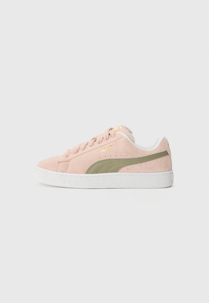 Pink suede sneaker with green accents and white rubber sole. Features delicate stitching and perforations, with gold branding on the side.