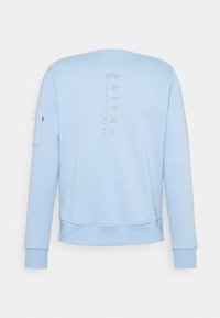 Felpa azzurra con polsini e fondo a costine, dotata di una piccola tasca laterale e logo verticale "ALPHA INDUSTRIES" sulla parte posteriore.