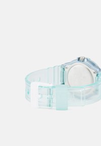 Montre Casio avec un bracelet en silicone transparent bleu et blanc, boîtier en métal argenté et cadran rond. Dispose d'une fermeture à boucle standard.