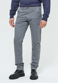 Pantalons en coton gris mélangé avec une coupe slim, poches avant et fermeture à bouton, associés à des bottes noires à lacets.