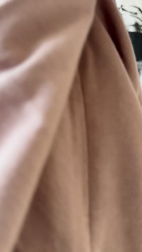 Um tecido rosa suave e amortecido cai gentilmente, com uma textura suave e um brilho subtil, exibindo linhas limpas e uma silhueta elegante.