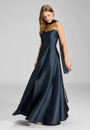 Elegante vestido azul marino de satén con escote recto, falda fluida, abertura lateral y detalles transparentes en los brazos. Acabado suave y ajuste entallado.