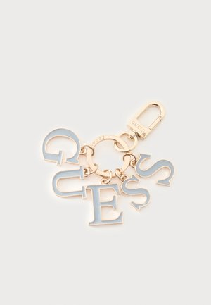 Nøglering i guldfarve med hvide emaljebogstaver, der staver "GUESS", fastgjort til en rund ring og en fjederlås.