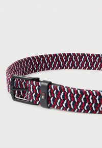 Πλεκτή ζώνη σε ναυτικό, κόκκινο και λευκό χρώμα με μαύρη πόρπη και δερμάτινο βρόχο που διαθέτει ένα μικρό ορθογώνιο λογότυπο.