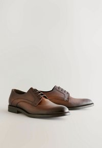 Brown leather dress shoes with a smooth finish, round toe, and contrasting stitched accents. Features 5 laces and a low, flat heel.