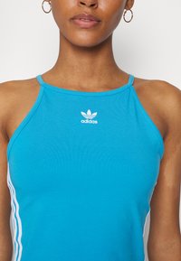 Mėlynas halteris, pagamintas iš tamprių audinių. Puošia mažas baltas Adidas logo ant krūtinės ir baltos juostos iš šonų.