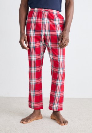 Røde ternede pyjamasbukser med elastisk taljebånd, med hvide og blå linjer i et rutemønster, lavet af et blødt stof.