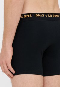 Černé bavlněné boxerky s širokým elastickým pasem, na kterém je zlatě vyražen nápis "ONLY & SO SONS", těsně přiléhající střih a minimální švy.