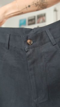 Tumši zili bikses ar teksturētu audumu, priekšējo pogu aizdari un izšuvumu detaļām jostasvietā un kabatās.