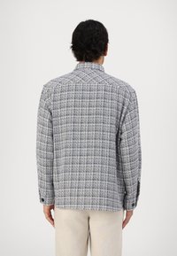 Rutete blazer i marineblått og hvitt stoff; har krage, lange ermer og knappemansjetter; teksturert vev med en strukturert passform.