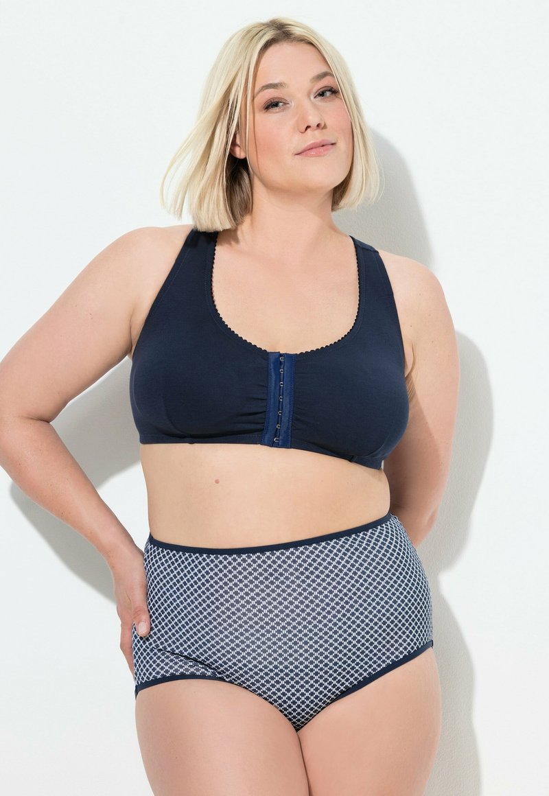 Granatowy miękki stanik z zapięciem z przodu i falbano-kształtnymi brzegami, w połączeniu z wysokim stanem granatowymi i białymi majtkami w wzory.