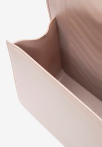 Interno della borsa di colore rosa chiaro, lucido, con una texture liscia. Presenta un unico scomparto e una tasca con bordo curvo per la organizzazione.