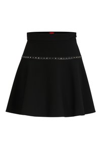 Zwarte uitlopende rok van rekbaar materiaal, met een smalle tailleband en een zilveren studs accent langs de zoom. Soepele textuur.