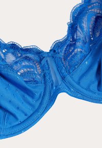 Blauwe kanten beha met semi-transparant materiaal, fijn kanten randje, polkadot textuur en een klein strikje in het midden aan de voorkant.