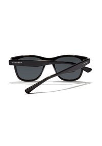 Ochelari de soare rectangulari negri cu lentile închise la culoare și denumirea mărcii "HAWKERS" pe ambele brațe, expuși pe un fundal alb.