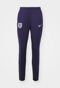 Pantalones deportivos de la Marina con banda elástica en la cintura, diseño de pierna ajustada, logo de Nike en blanco y un escudo de la selección de fútbol de Inglaterra en el muslo izquierdo.