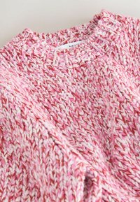 Knit sweater in pink and white hues with a textured pattern. Features a crew neck and visible label sewn at the collar.