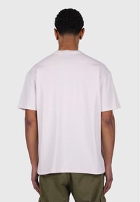Camiseta de manga corta y cuello redondo en algodón rosa claro. Presenta un corte relajado, dobladillo recto y detalles de costura mínimos.