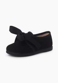 Pantofii din velur negru au vârful rotund, talpa plată și un accent proeminent sub formă de fundă dintr-o panglică neagră asortată. Dispun de un design cu curea sigur.