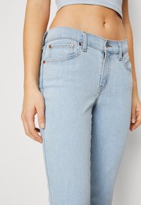 Light blue denim jeans featuring a classic fit, five-pocket design, and contrasting stitching. The fabric has a smooth texture with subtle detailing.