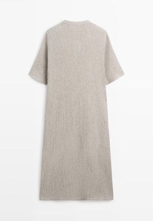 Długa, jasnobeżowa sukienka z krótkim rękawem, o prostym kroju i fakturowanej tkaninie, pokazana od tyłu na białym tle.