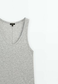 Débardeur gris clair sans manches avec un col en V posé à plat sur un fond blanc, montrant la texture du tissu et la couture centrale.