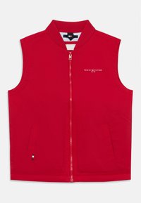 Röd ärmlös jacka med hög krage, framdragkedja, två sidfickor och vitt "TOMMY HILFIGER"-logotyp. Slätt, lätt material.