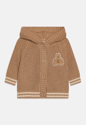 Cardigan bébé marron en tricot avec capuche, quatre boutons, poignets et ourlet à rayures blanches, et patch écusson teddy avec la lettre G sur la poitrine.