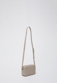 Beige crossbodytas van glad leer, met een rechthoekige vorm, verstelbare riem en ritssluiting. Subtiele metalen accenten.