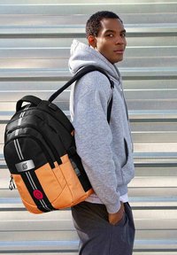 Mochila negra y naranja con múltiples compartimentos con cremallera, rayas y logotipo. Tejido texturizado, correas acolchadas y diseño robusto.