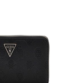 Portefeuille en simili cuir noir avec un motif gaufré, fermeture éclair argentée et une plaque logo triangulaire portant "GUESS USA".