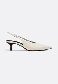Escarpin slingback en cuir blanc à talon kitten, bout pointu et bride réglable avec boucle sur fond clair.