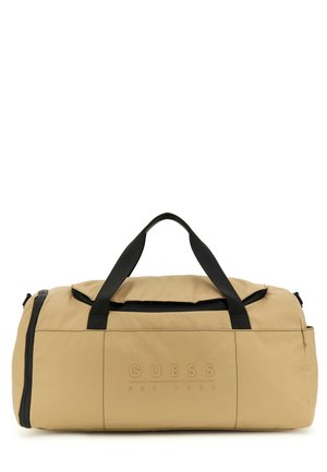 Sac de sport beige en nylon avec des accents noirs, doté d'un logo à l'avant, de deux poignées supérieures et d'un compartiment principal zippé.