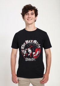 Zwarte katoenen t-shirt met een kleurrafische "Scooby-Doo" afbeelding met drie vrouwelijke personages, vetgedrukte tekst en een circulair ontwerp.