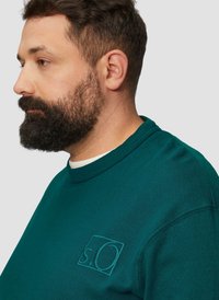 Sweat-shirt vert à col rond avec logo brodé. Fabriqué en tissu doux, il présente une coupe décontractée et un col côtelé pour plus de confort.