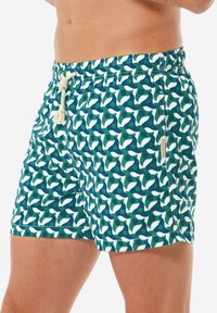 Pantaloni da bagno con un motivo astratto verde, blu e bianco. Presentano una vita elasticizzata con cordino e una tasca laterale.