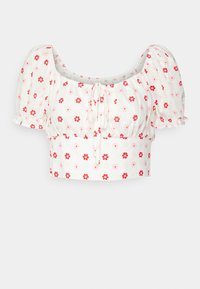 Top corto bianco con maniche a sbuffo, scollo rotondo e stampa floreale in rosso e rosa. Il materiale sembra leggero e con una texture.