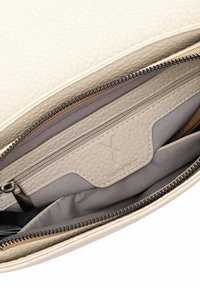 Interno di una borsa in pelle beige testurizzata con compartimenti con zip; foderato grigio e dettagli di branding discreti; zip in metallo e accenti marroni.