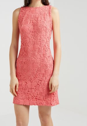Ärmelloses korallenrosa Spitzenkleid mit Blumenmustern, tailliertem Schnitt und knielangem Saum, getragen von einer Frau vor hellem Hintergrund.