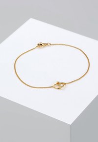 Bracelet en or avec une chaîne fine et torsadée, présentant deux cœurs entrelacés au centre et une fermeture à mousqueton.