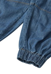 Pantaloni din denim cu un tiv strâns, de culoare albastru deschis, având detalii de cusătură vizibile care creează un aspect texturat.